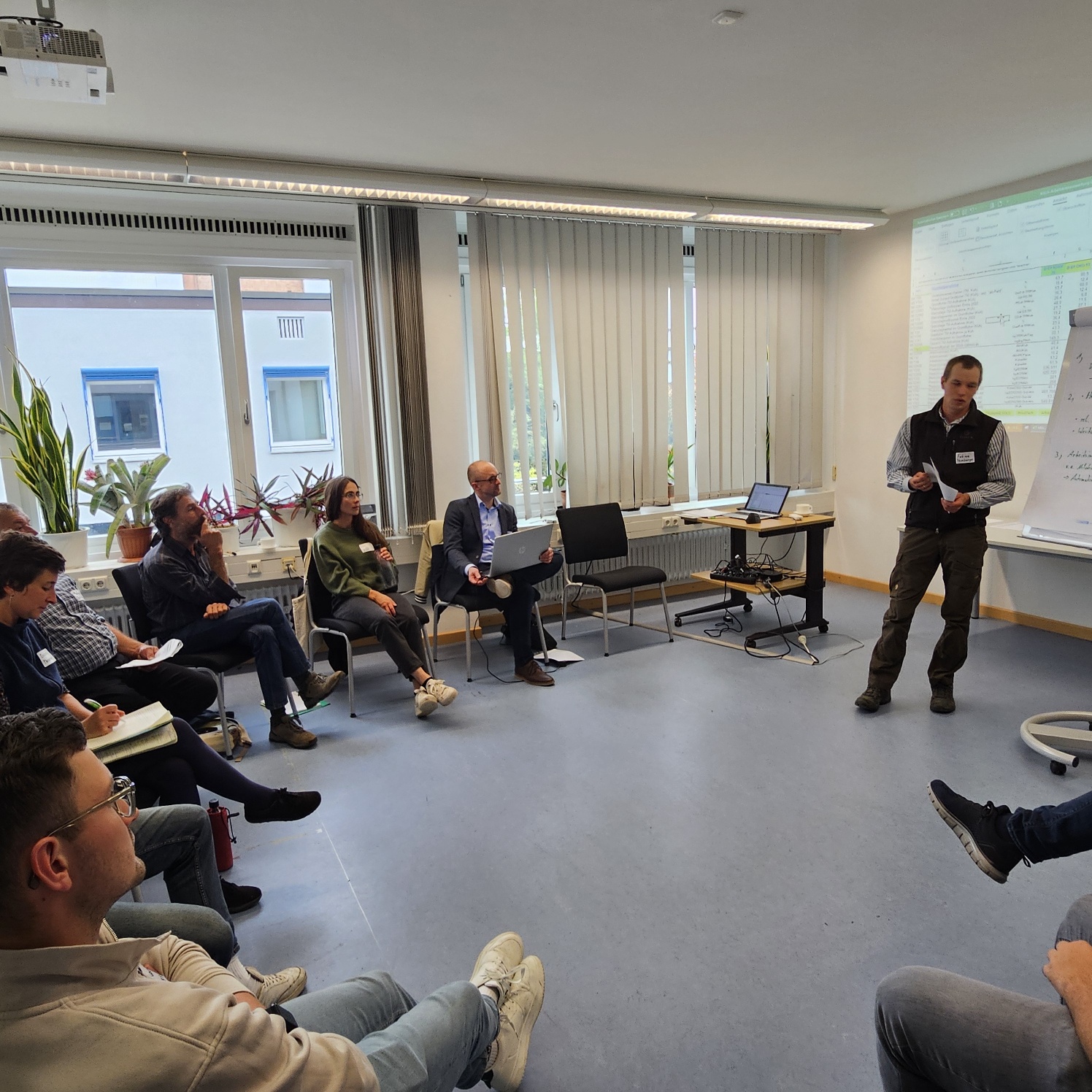 Menschen in einem Stuhlkreis während einer Präsentation