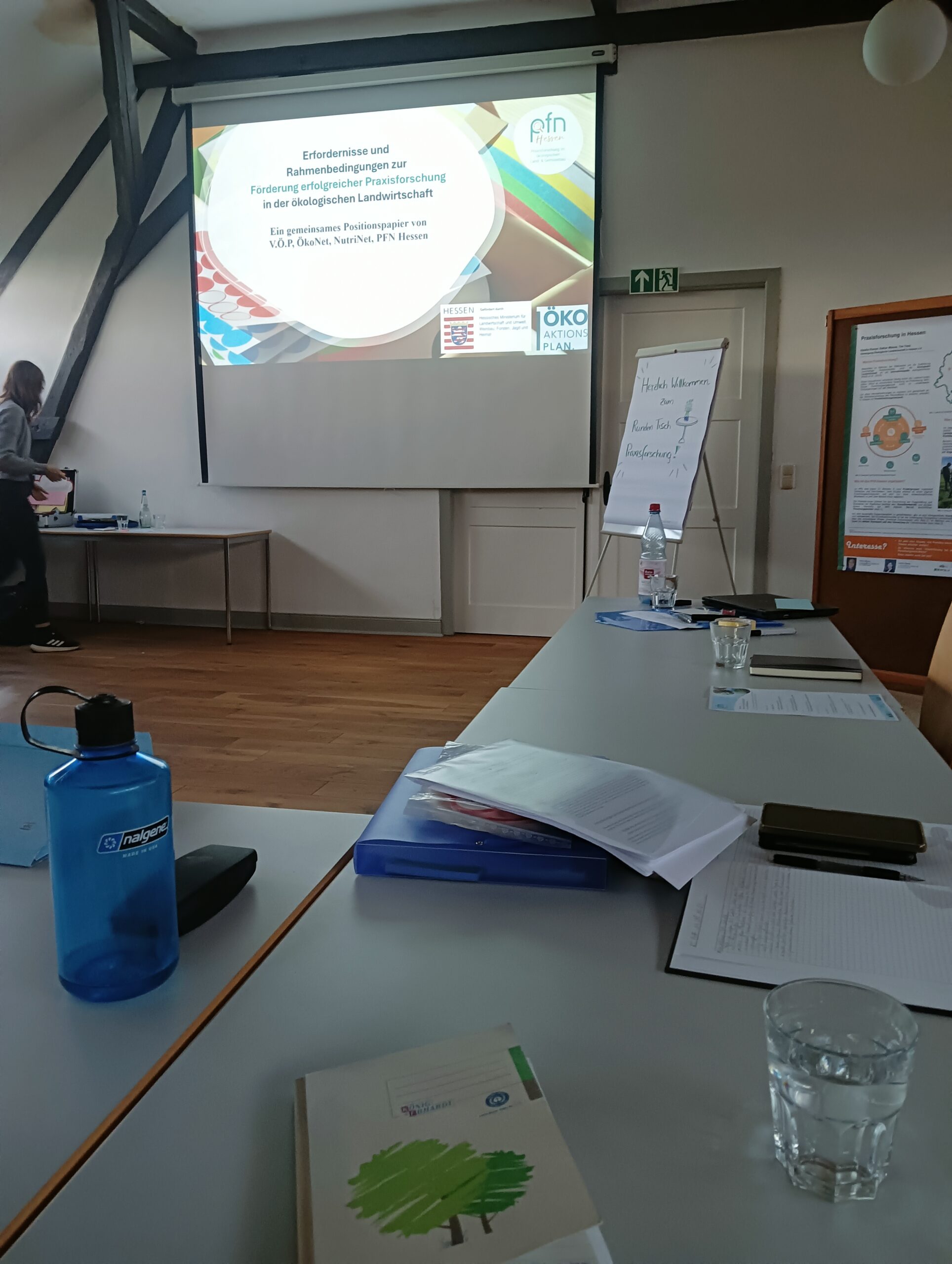 Tisch mit Arbeitsmaterial vor einer Präsentation